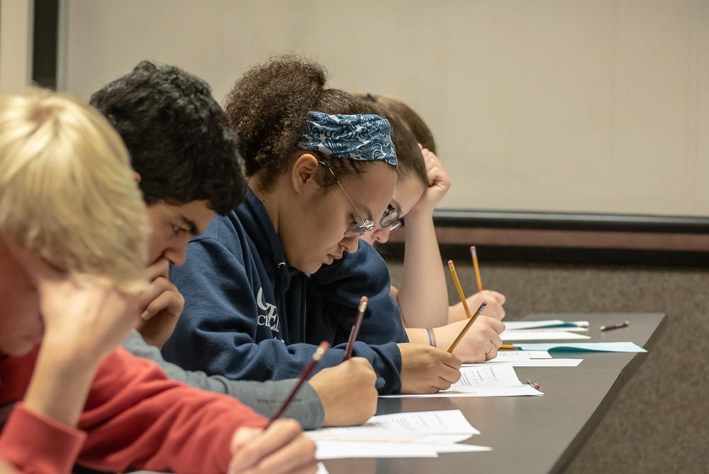 Students taking a written test with pencil and paper