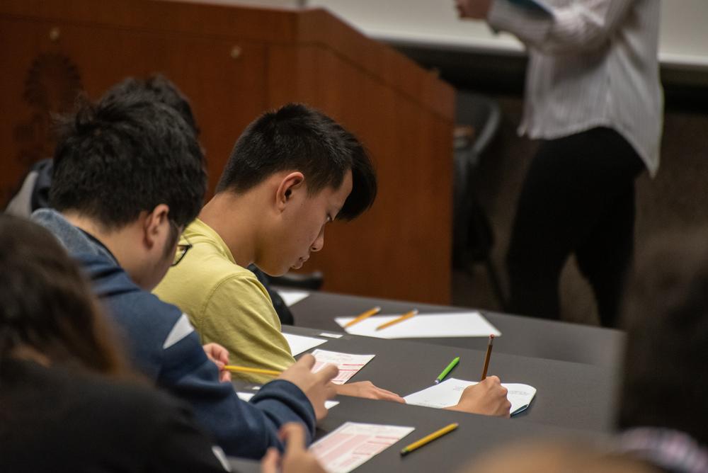 Students taking a written test with pencil and paper