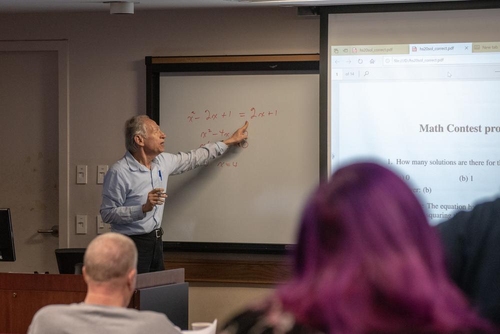 Professor solving a math problem at the white board