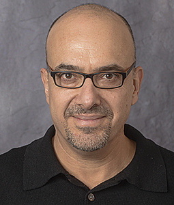 Amit Almor wearing glasses and a black polo shirt
