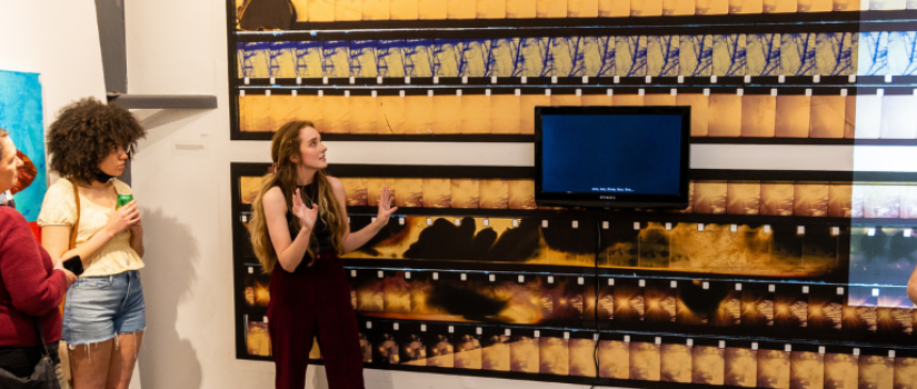 A female student gives an artist talk in front of a video installation at Stormwater Studios.