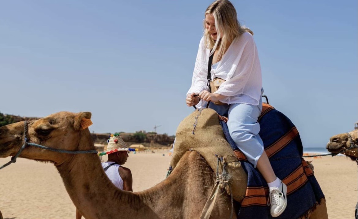 Student riding camel in desert