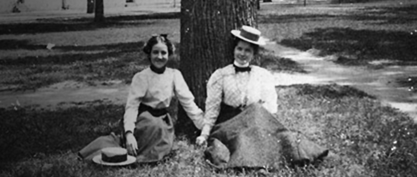 Historic photo of two women on the horseshoe in gowns and hats. 