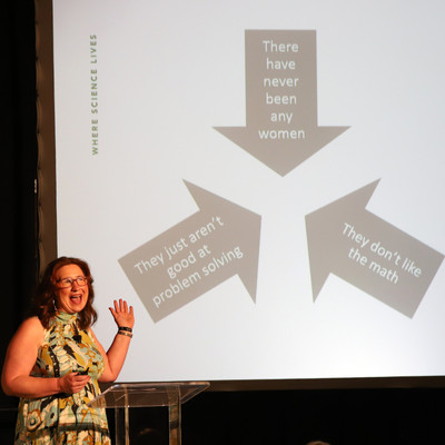 On a lecture screen: three arrows pointing to each other which read "there have never been any women, they just aren't good at problem solving, and they don't like the math"