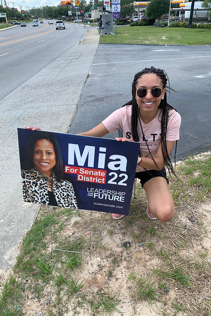 Lauren Harper kneels in front of a sign for S.C. Sen. Mia McLeod, whose campaign she managed in 2020.