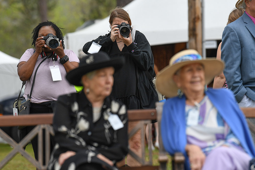 Students Altasia Johnson, back left, and Tori Wright, frame a photograph through spectators enjoying a day at the races at the 88th Running of the Carolina Cup in Camden, S.C.