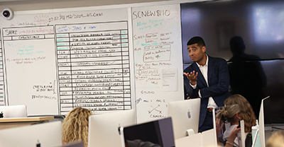 Allen Devlin speaking to a class in front of the schedule whiteboard
