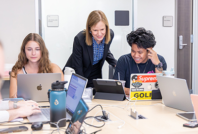 students working at computer with a faculty member