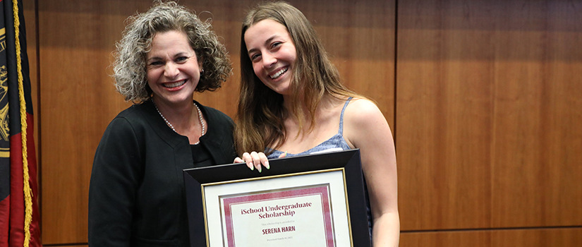Serena Harn poses with Elise Lewis while holding her certificate reading "iSchool Undergraduate Scholarship."
