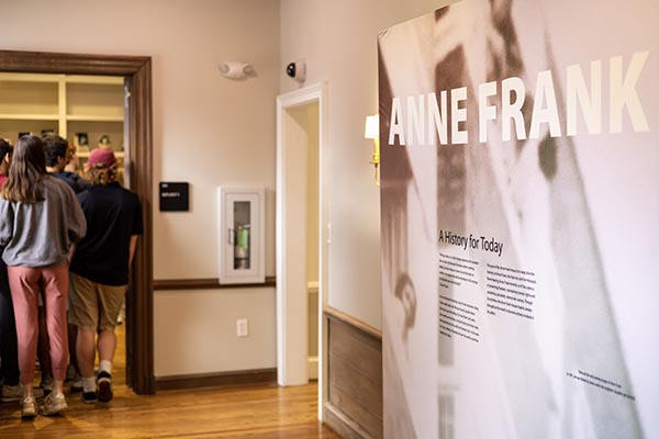 A wall of the Anne Frank Center. A University 101 group passes through a door to the left.