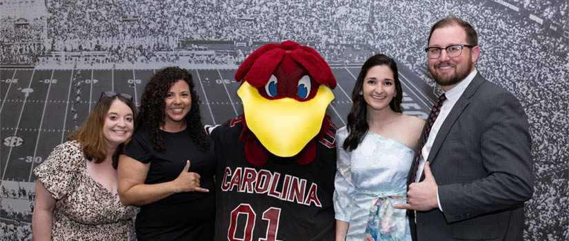 Smiling people standing with Cocky