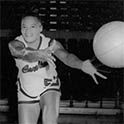 Smiling woman with arms out. A basketball approaches her from the right.