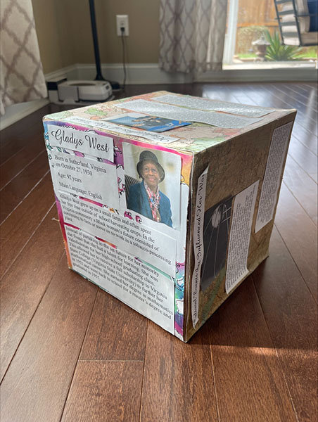 cube made from paper and cardboard, decorated with articles and photos of Gladys West