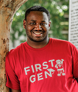 Curtis Pernell wearing a red t-shirt that says "First Gen" on it