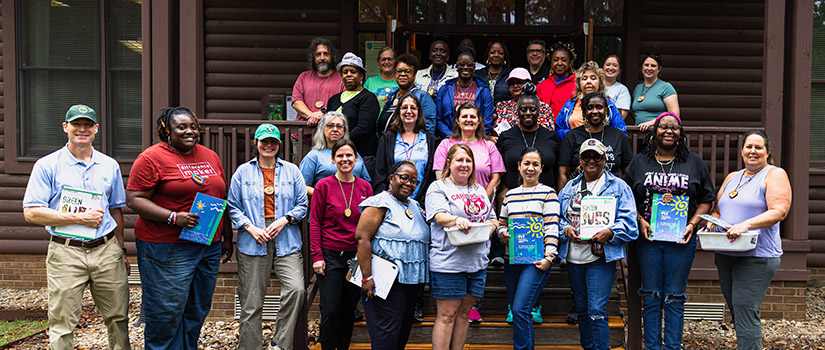 group of teachers standing in front of a cabin