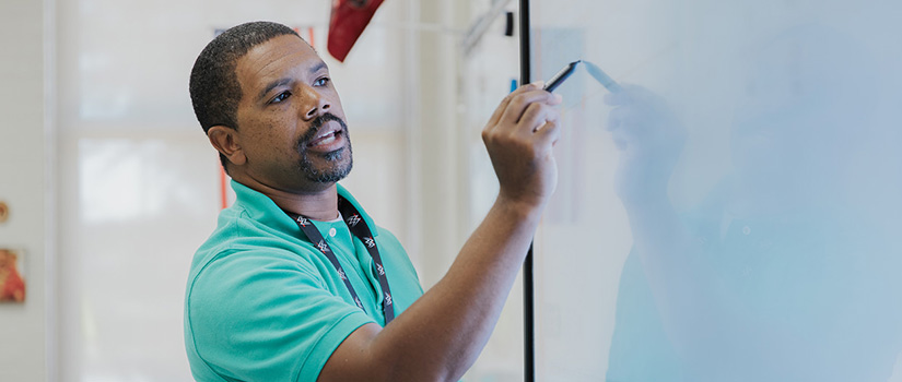 An African American teacher writing on a whiteboard