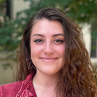 A brown-haired white woman in an outdoor setting
