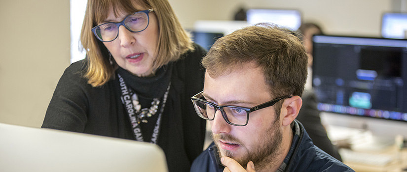 a teacher guides a student at a computer
