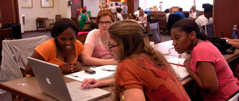 several female students looking at a laptop computer