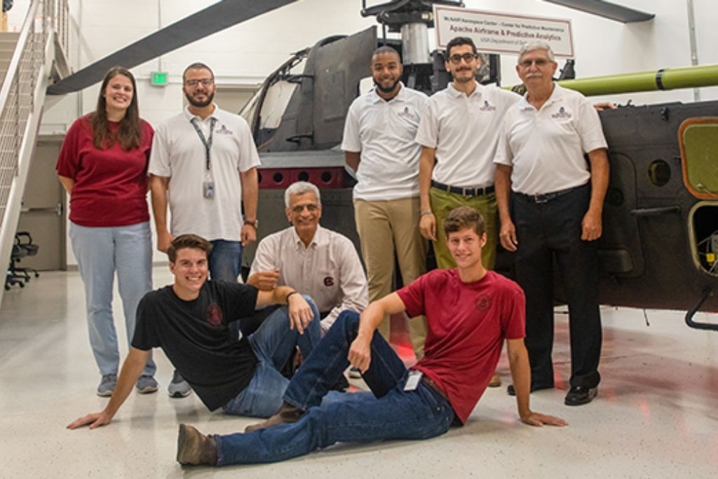 Faculty and students standing by helicopter in the McNair Center