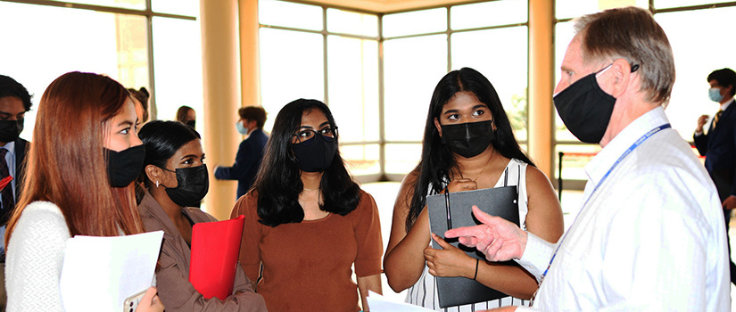 A recruiter talking to three female students, all wearing face masks