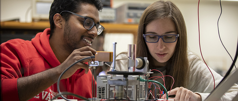 a male student and a female student work on an electrical device together during class