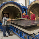 a student and two faculty members inspect material ready for the composite machine