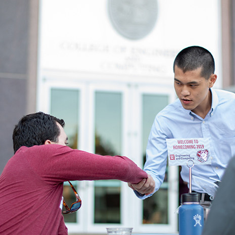 An alum shakes hands with a student