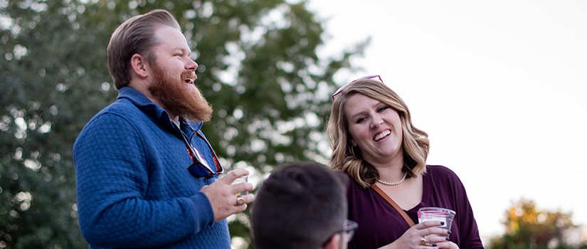 a man and woman alumni laughing outdoors