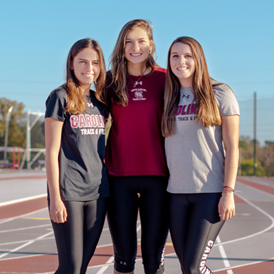 three female track athletes pose on the track