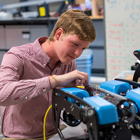 a student works on a medium sized blue robot