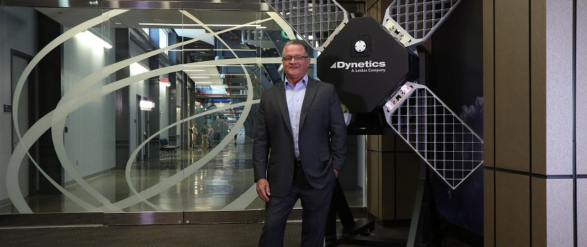David King stands in front of the Dynetics logo.