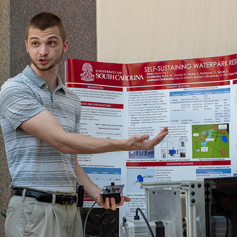 a student presents his research poster outside the Swearingen building.
