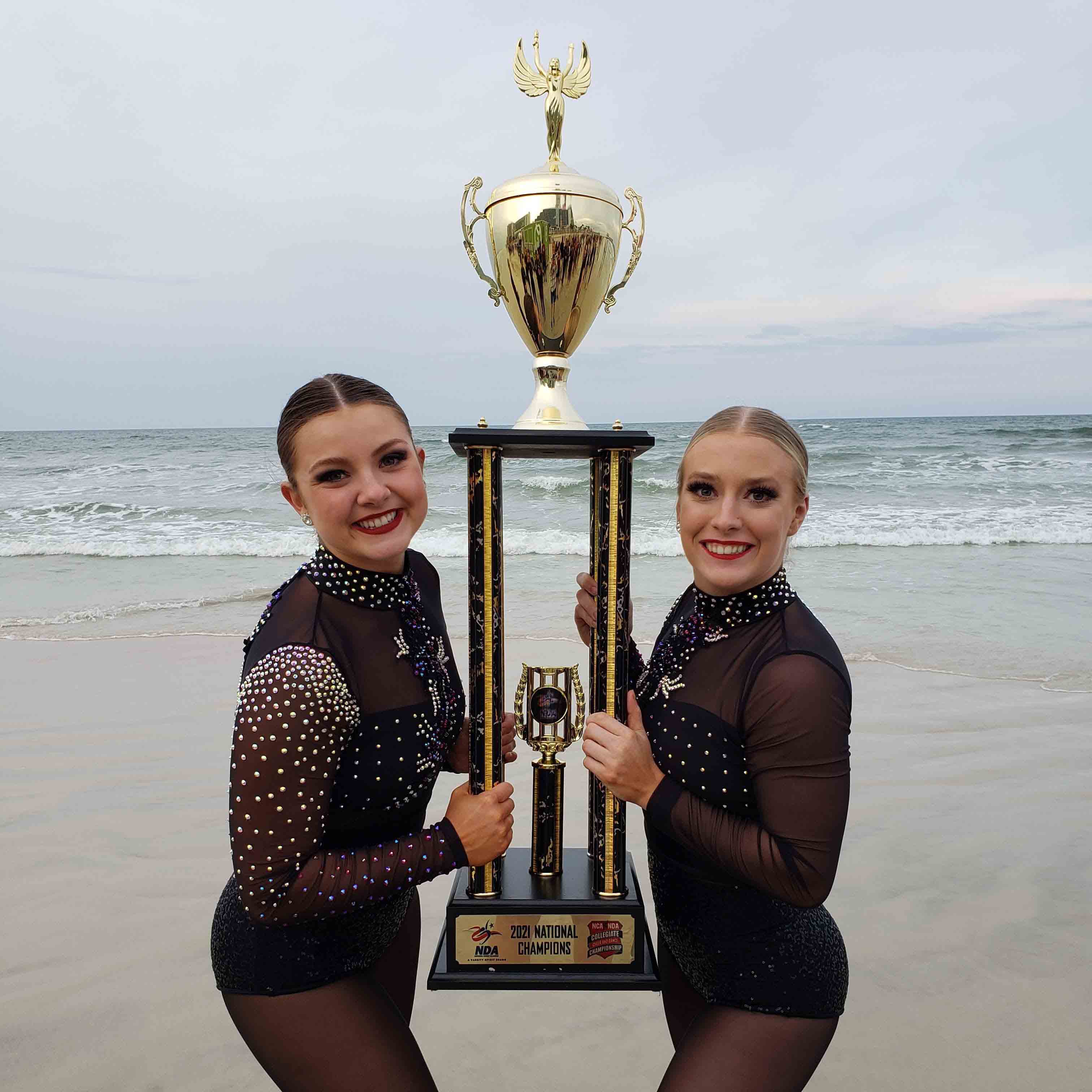 Two Carolina Girls holding trophy on beach