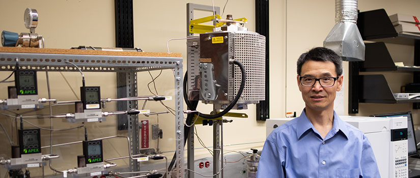 Mechanical Engineering Professor Fanglin (Frank) Chen stands in his lab next to equipment