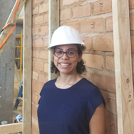 Female graduate student standing in front of wall with hard hat on