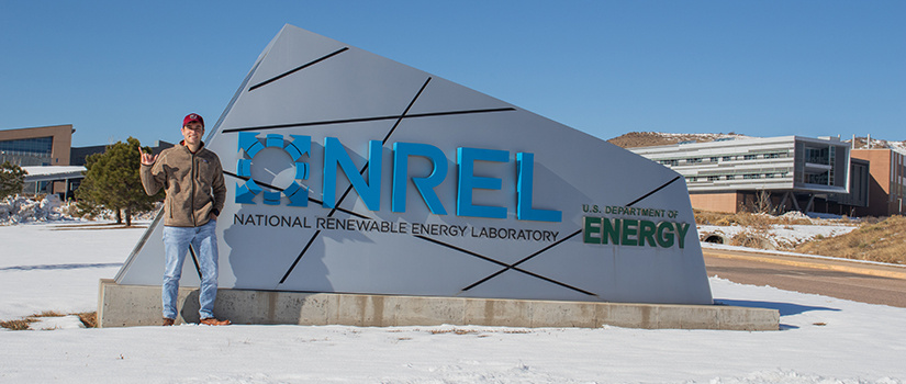 Drew Pereira stands in front of NREL's sign.