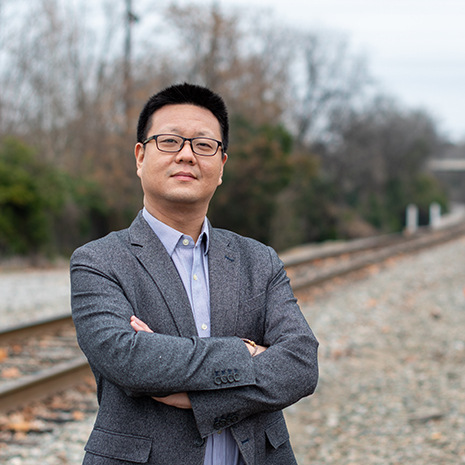 Yu Qian stands in front of the railroad.