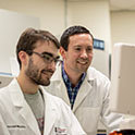 Dr. Michael Gower in lab leaning over shoulder of graduate student.
