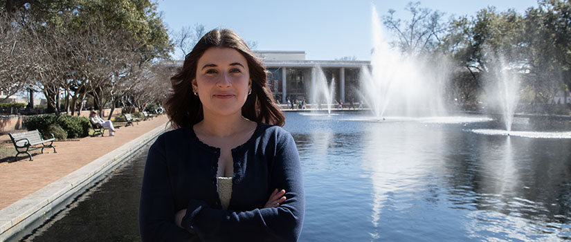 Soraya Remaili standing in front of the fountain in front of the Thomas Cooper Library