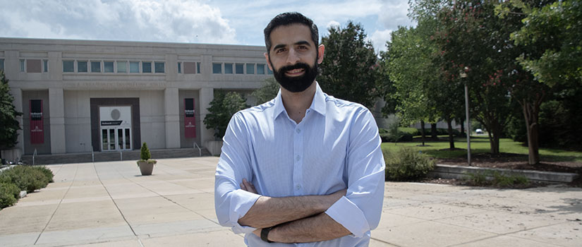 Graduate student Alireza Mashreghi stands with the front entrance of the Swearingen building in the background.