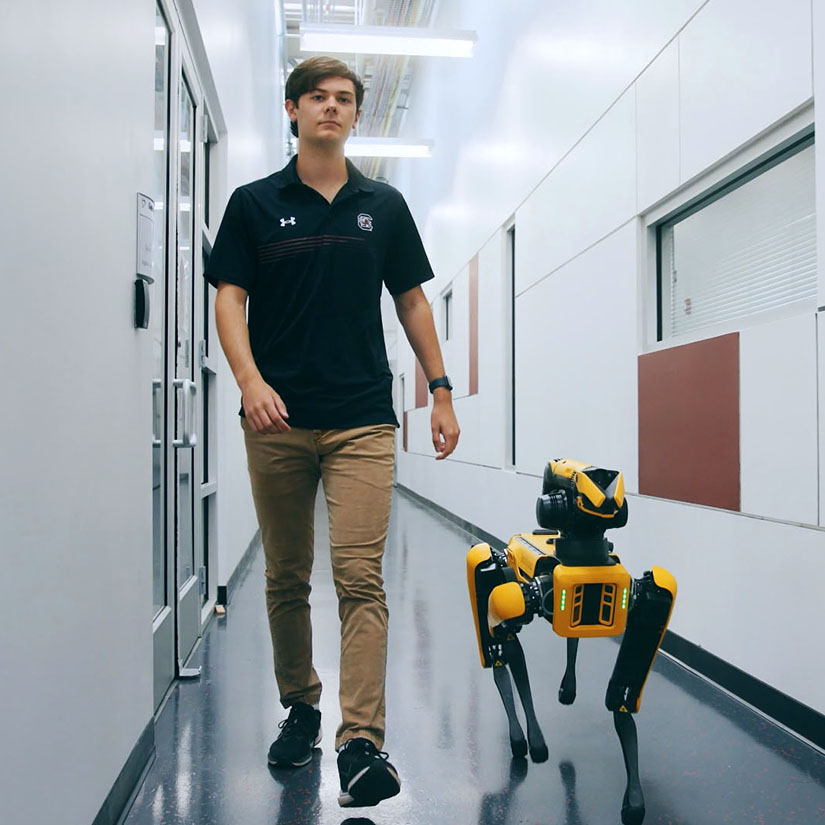 Braden Guilian walking with a SPOT robotic dog. 
