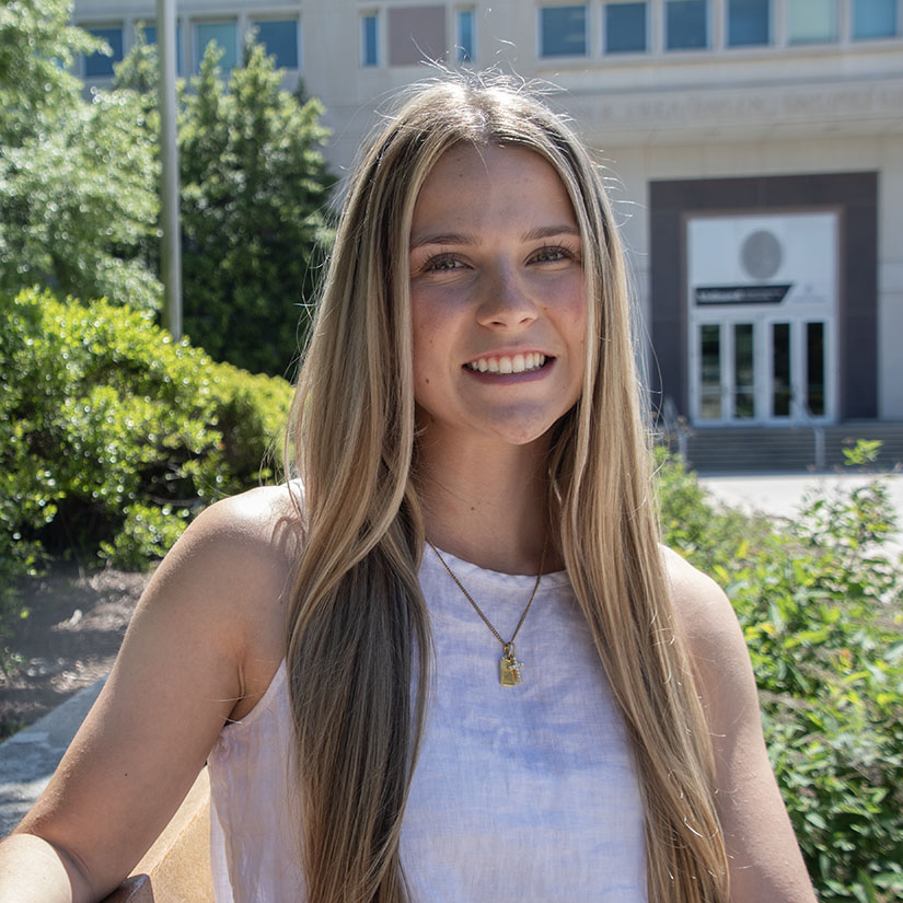 Student Ciarra Lorusso sitting on a bench outside of the front entrance to Swearingen. 
