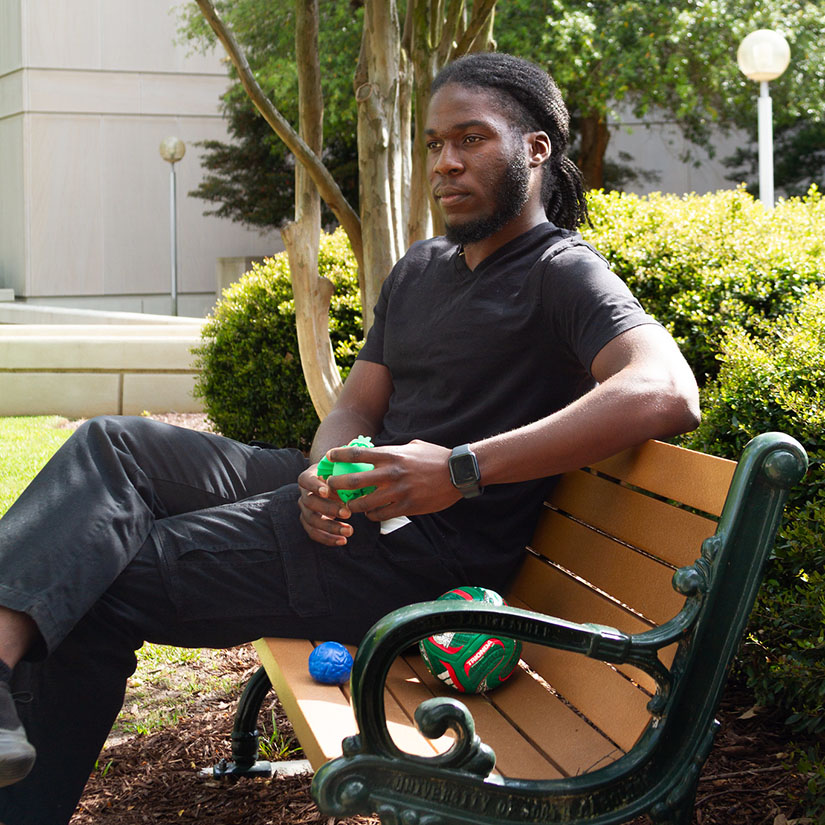 Francesco Yigamawano sits on a bench outside of the Swearingen Engineering Center. 