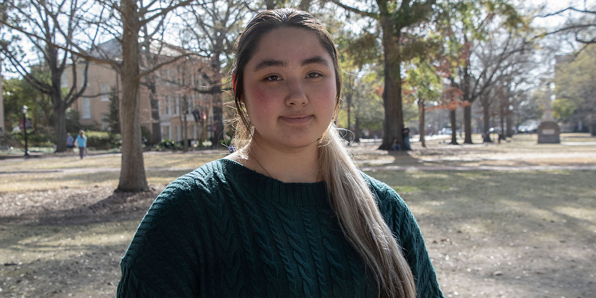 Young woman in a green sweater standing on USC's Historic Horseshoe