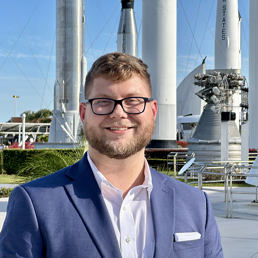 Michael Cargill headshot standing in front of rockets.