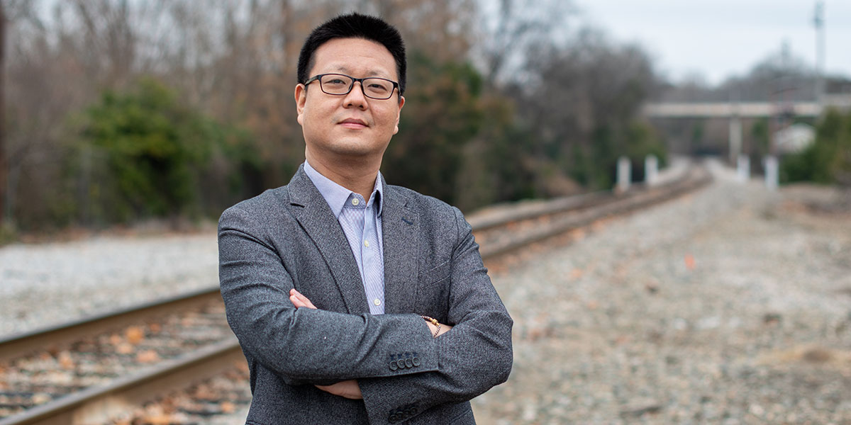 Civil Engineering Professor Yu Qian with railroad tracks in the background. 