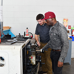 Image of two men working with a machine in the machine shop.