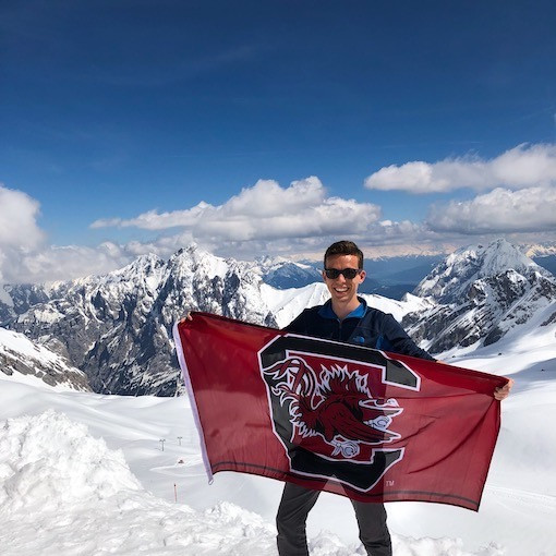 Honors student on top of snow covered mountain with Gamecock flag