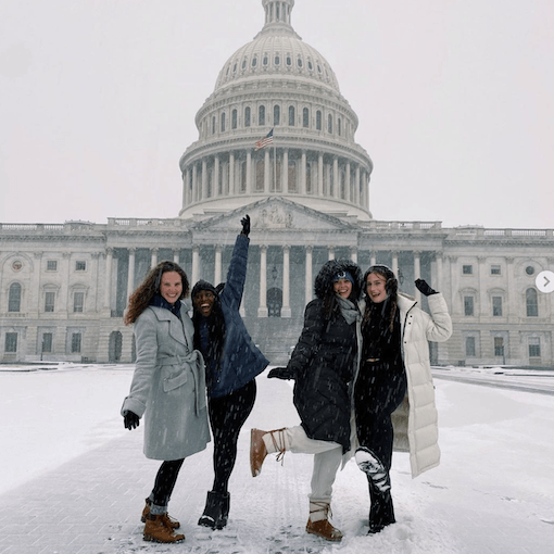 Four female students in the snow in front of the U.S. Capital building